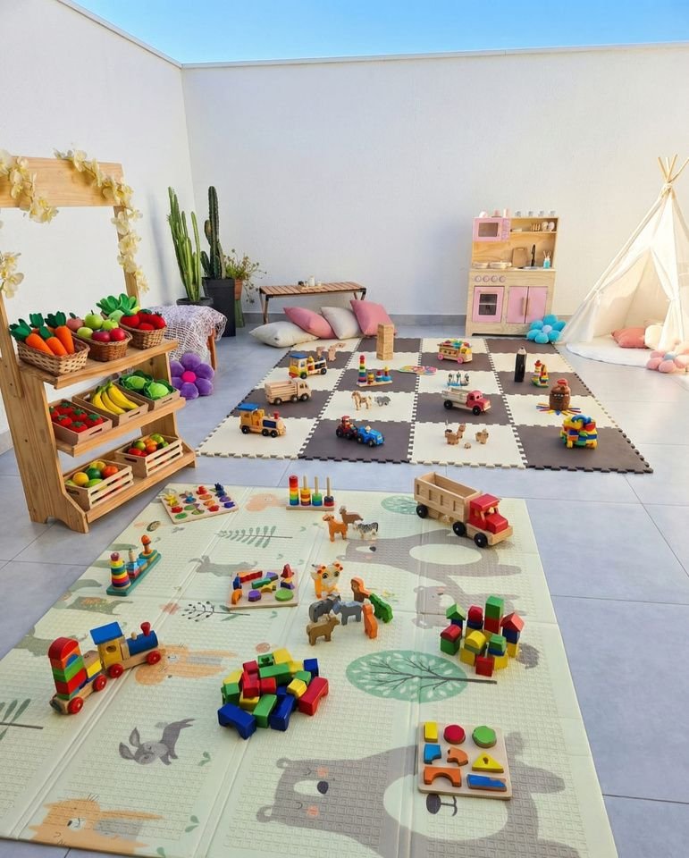 Sala montada com tapete de atividades, prateleira de frutas e brinquedos